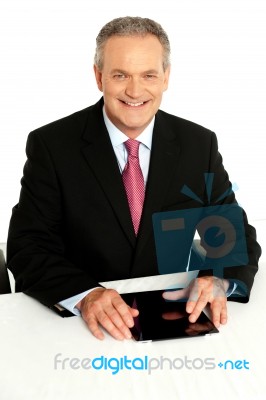 Senior Businessman Sitting With Tablet On Desk Stock Photo