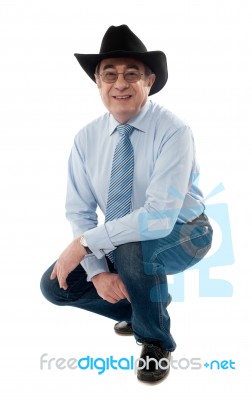 Senior Cowboy Squatting Stock Photo