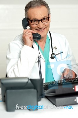 Senior Doctor Talking Over Phone Stock Photo