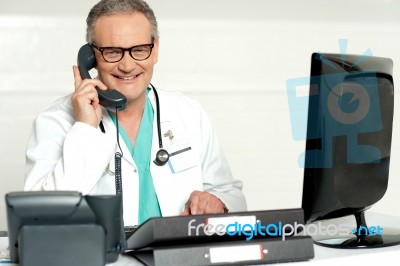 Senior Doctor Talking Over Phone Stock Photo