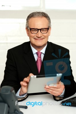 Senior Executive Sitting With Tablet Pc In Hands Stock Photo