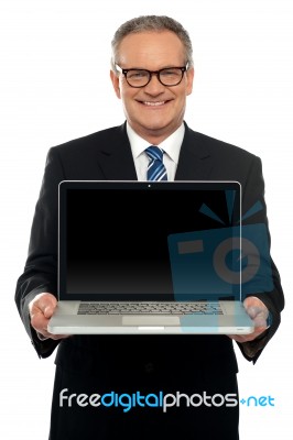 Senior Executive Standing With Open Laptop Stock Photo