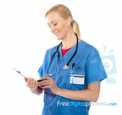 Senior Female Doctor Writing Report Stock Photo