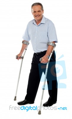 Senior Man Standing With Crutches Stock Photo