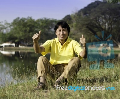 Senior Man With Thumb Up Against A Green Park Stock Photo