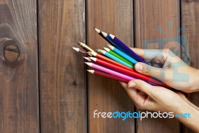 Set Of Colored Pencils In Female Hands On A Background Of Dark W… Stock Photo