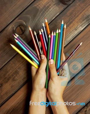 Set Of Colored Pencils In Female Hands On A Background Of Dark W… Stock Photo