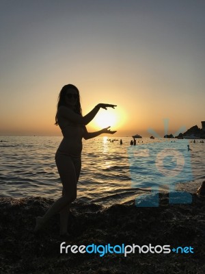 Sexy Woman Silhouette Standing In The Sand During A Sunset On Golden Bay, Malta Stock Photo