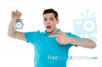 Shocked Young Guy Holding Alarm Clock Stock Photo