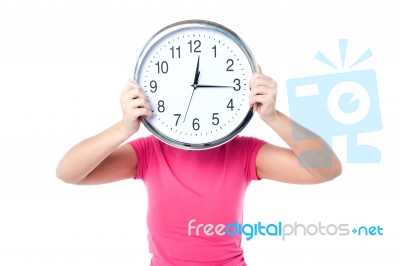 Shy Girl Hiding Her Face With Wall Clock Stock Photo