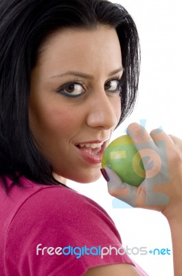 Side Pose Of Smiling Female Eating Apple Stock Photo