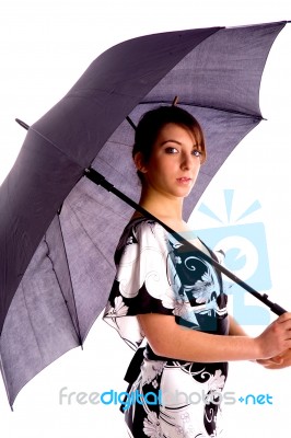 Side Pose Of Young Woman Holding An Umbrella Stock Photo