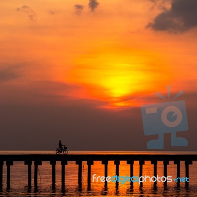 Silhouette Boy Ride Bicycle On The Bridge At Sunset Stock Photo