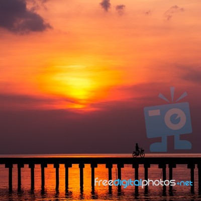 Silhouette Boy Ride Bicycle On The Bridge At Sunset Stock Photo