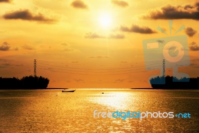 Silhouette High Voltage Electricity Pylon At Sunset Over The Sea… Stock Photo