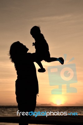 Silhouette mom with child at sunset Stock Photo