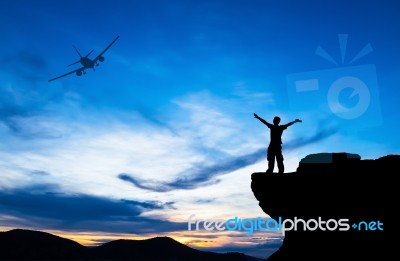 Silhouette Of A Man On The Rock And Silhouette Commercial Plane Stock Photo