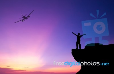 Silhouette Of A Man On The Rock And Silhouette Commercial Plane Stock Photo