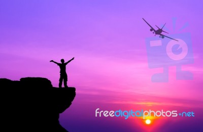 Silhouette Of A Man On The Rock And Silhouette Commercial Plane Stock Photo