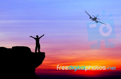 Silhouette Of A Man On The Rock And Silhouette Commercial Plane Stock Photo