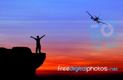 Silhouette Of A Man On The Rock And Silhouette Commercial Plane Stock Photo