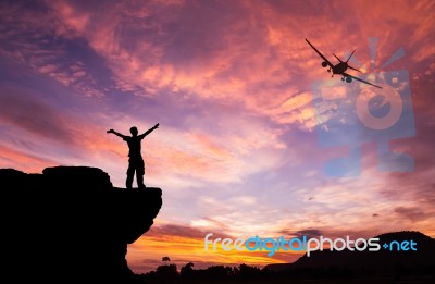 Silhouette Of A Man On The Rock And Silhouette Commercial Plane Stock Photo