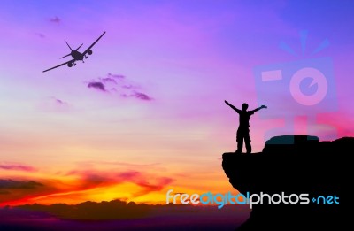 Silhouette Of A Man On The Rock And Silhouette Commercial Plane Stock Photo