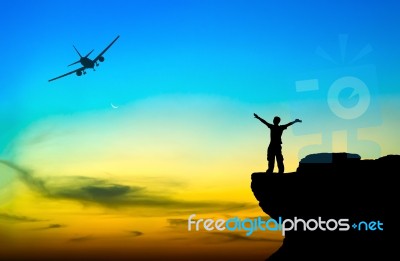 Silhouette Of A Man On The Rock And Silhouette Commercial Plane Stock Photo