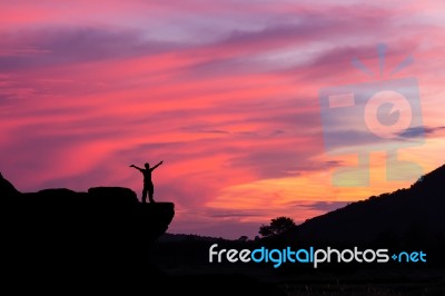 Silhouette Of A Man On The Rock At Sunset Stock Photo