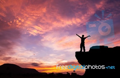 Silhouette Of A Man On The Rock At Sunset Stock Photo