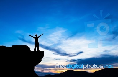 Silhouette Of A Man On The Rock At Sunset Stock Photo