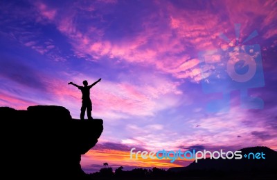 Silhouette Of A Man On The Rock At Sunset Stock Photo