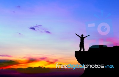 Silhouette Of A Man On The Rock At Sunset Stock Photo