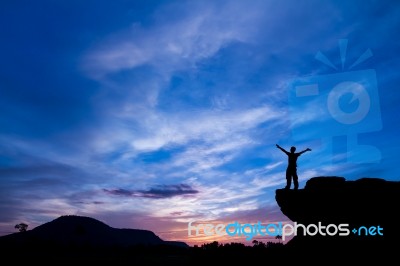 Silhouette Of A Man On The Rock At Sunset Stock Photo