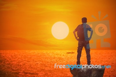 Silhouette Of Backpacker And Sunset In The Sea Stock Photo