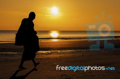 Silhouette Of Monk Walk On The Beach With Beutuful Stock Photo