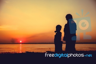 Silhouette Of Mother And Child Enjoying The View At Riverside Stock Photo