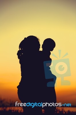 Silhouette Of Mother And Child Enjoying The View At Riverside Stock Photo