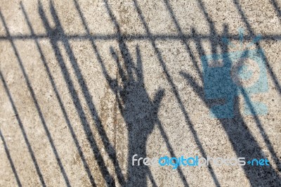 Silhouette Of Prisoner Hands In Jail Stock Photo