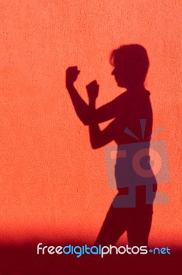 Silhouette Of Woman Showing Fists On Red Wall Stock Photo