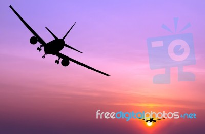 Silhouetted Commercial Airplane Flying At Sunset Stock Photo