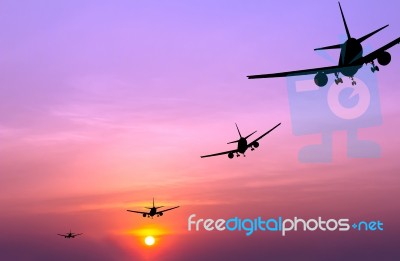 Silhouetted Commercial Airplane Flying At Sunset Stock Photo