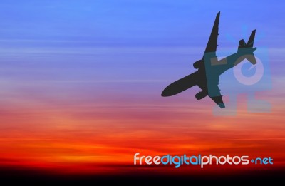 Silhouetted Commercial Airplane Flying At Sunset Stock Photo