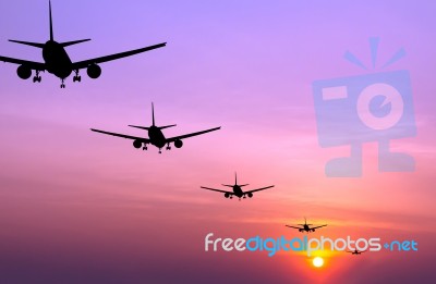 Silhouetted Commercial Airplane Flying At Sunset Stock Photo