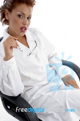 Sitting Female Doctor Holding Eyewear Stock Photo