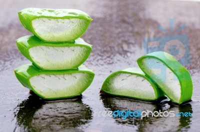 Slice Aloe Vera On Wet Wood Background Stock Photo