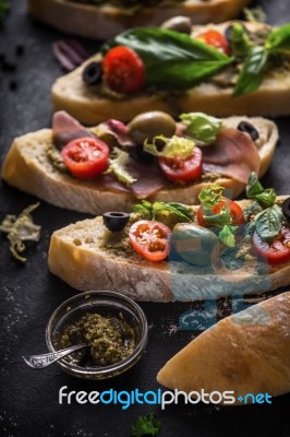 Slices Of Ciabatta With Olives , Tomatoes And Basil On The Black Stone Table Vertical Stock Photo