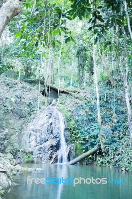 Small Waterfall Flowing Into A Calm Pool Of Water Stock Photo