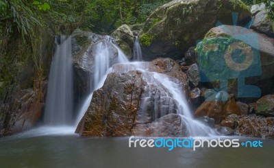 Small Waterfall With Red Big Stone In The Forest Stock Photo