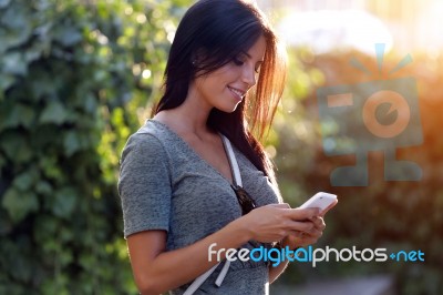 Smiling Beautiful Woman Texting With Her Phone In The Garden Stock Photo